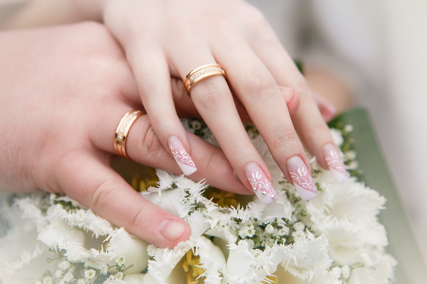 Mãos e anéis no buquê de casamento